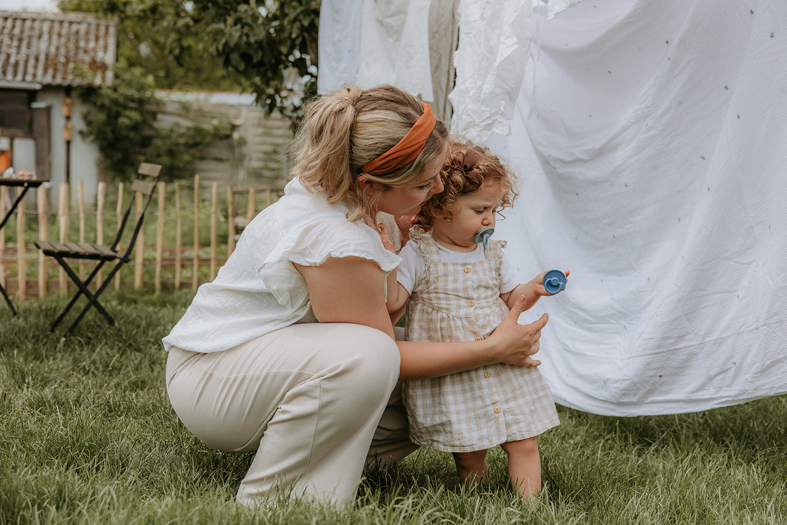 Woman and child outdoors, looking at a pacifier from the Frigg Rope Night pacifier 2-pack in latex in Stone blue sage