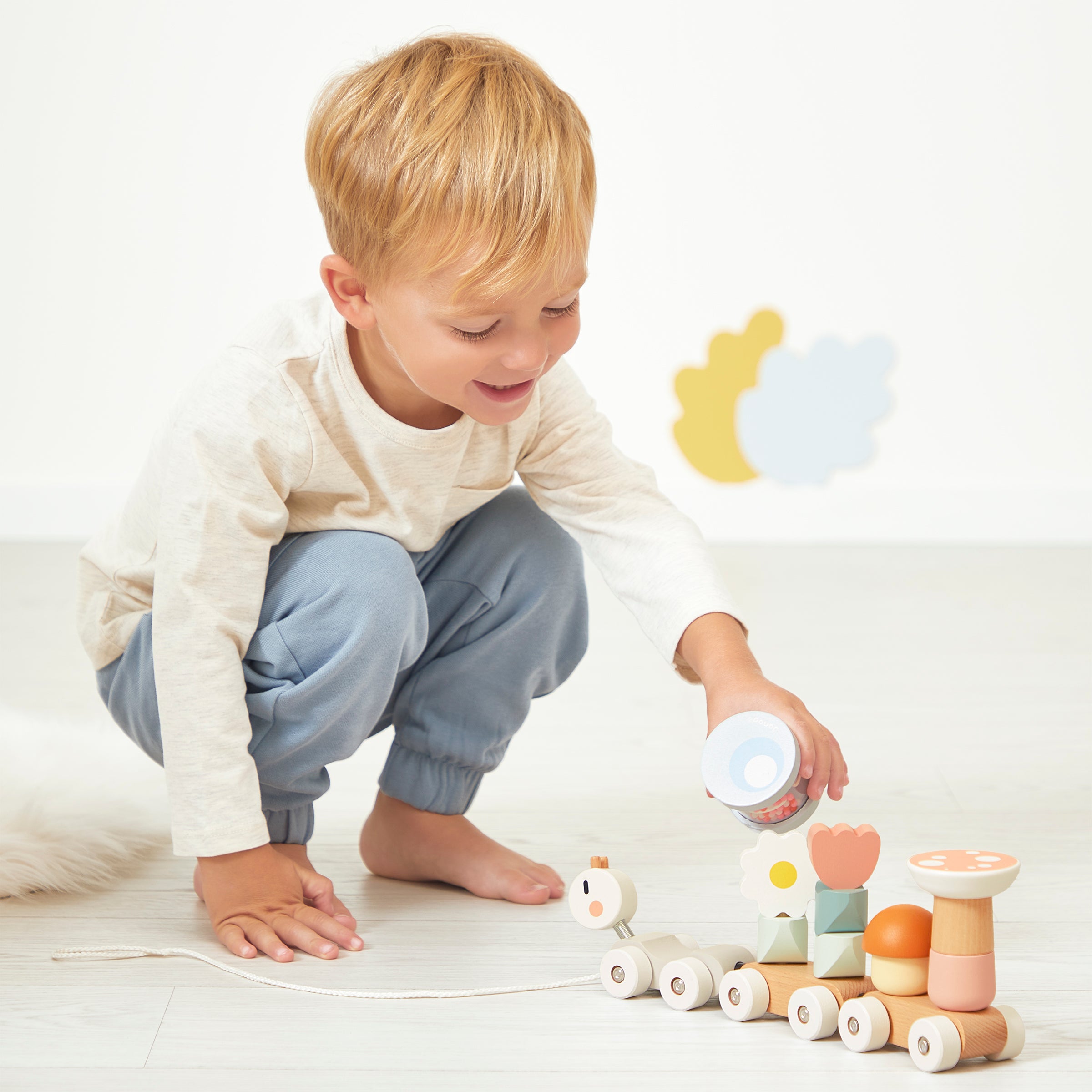 Child playing with Janod Pull along snail on a neutral background