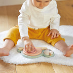 Child playing with Janod stackable sensory snail toy on a white rug