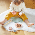 Child playing with Janod stackable sensory snail toy on a white rug