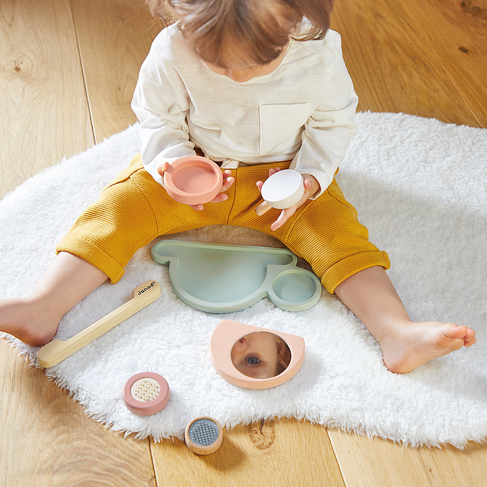 Child playing with Janod stackable sensory snail toy on a white rug