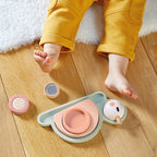 Janod stackable sensory snail toy with detachable parts next to child in yellow pants