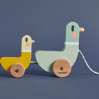Wooden duck toys by Janod for imaginative play on a blue background