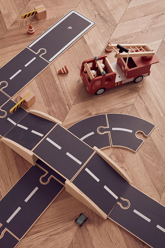 Toy fire truck (not included) on a wooden floor next to the Kids Concept car track extension