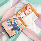 Lilliputiens Stella and her cuddle activity book on a pastel background