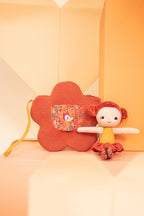 Lilliputiens Adèle doll with flower bag on an orange and peach background