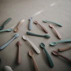 Mushie first feeding baby spoons 2-pack in Stone and Cloudy mauve styled with Mushie baby spoons in different colors