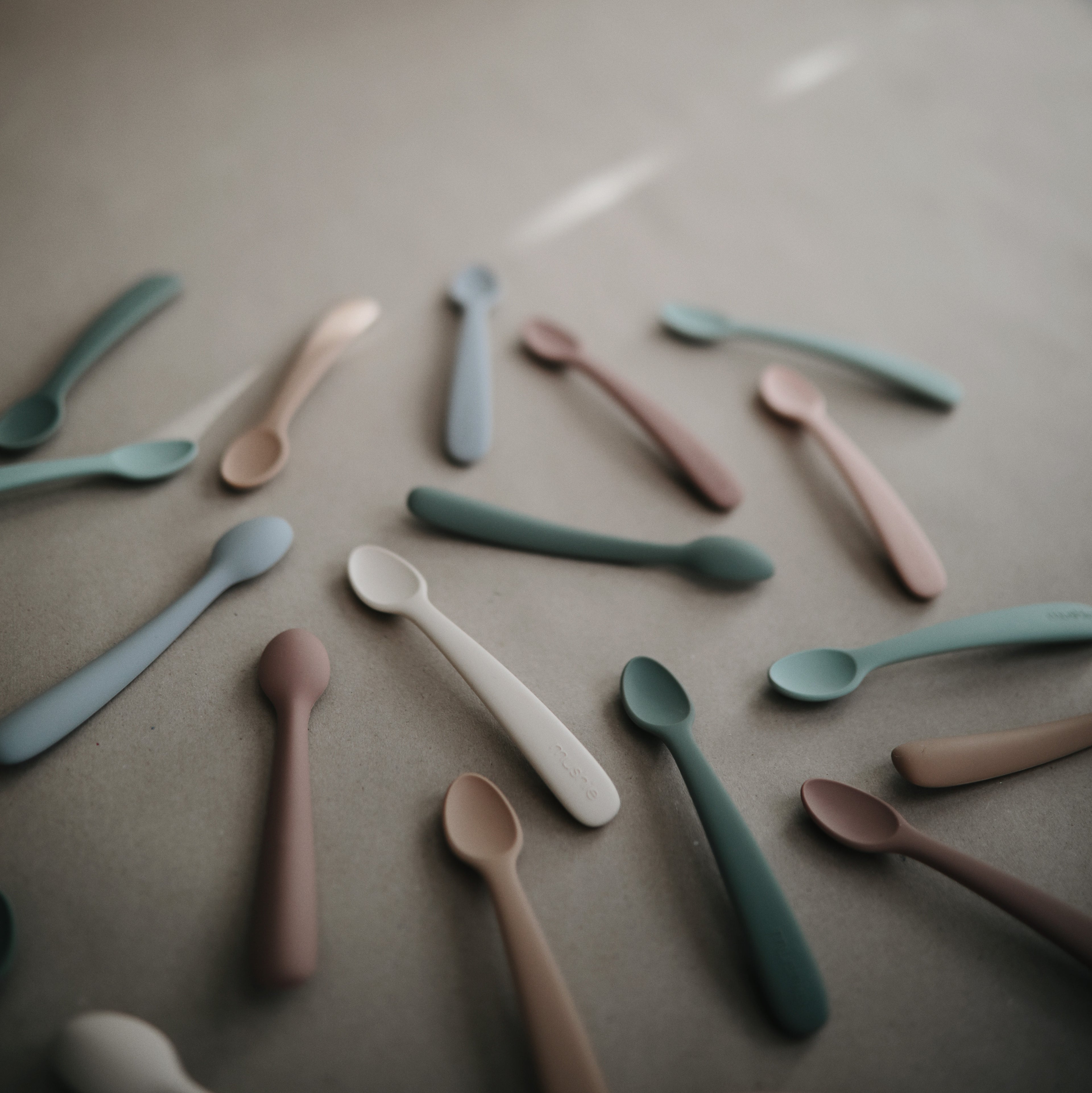 Mushie first feeding baby spoons 2-pack in Stone and Cloudy mauve styled with Mushie baby spoons in different colors