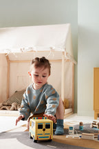 Child playing with a Kids Concept wooden toy ambulance in a bedroom