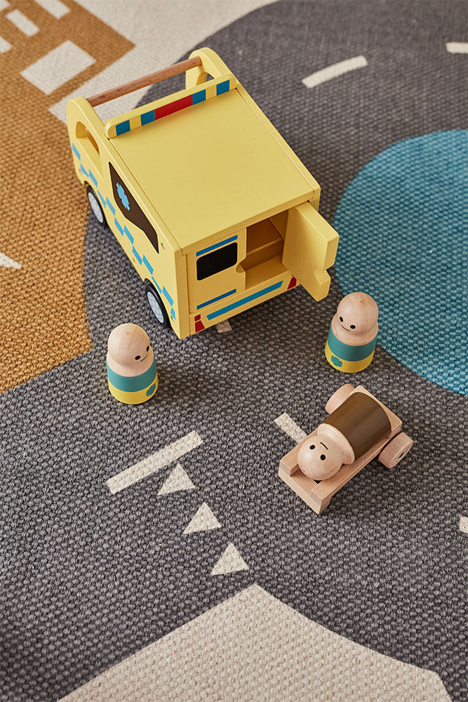 Kids Concept wooden toy ambulance on a road mat with small figures (included) around it