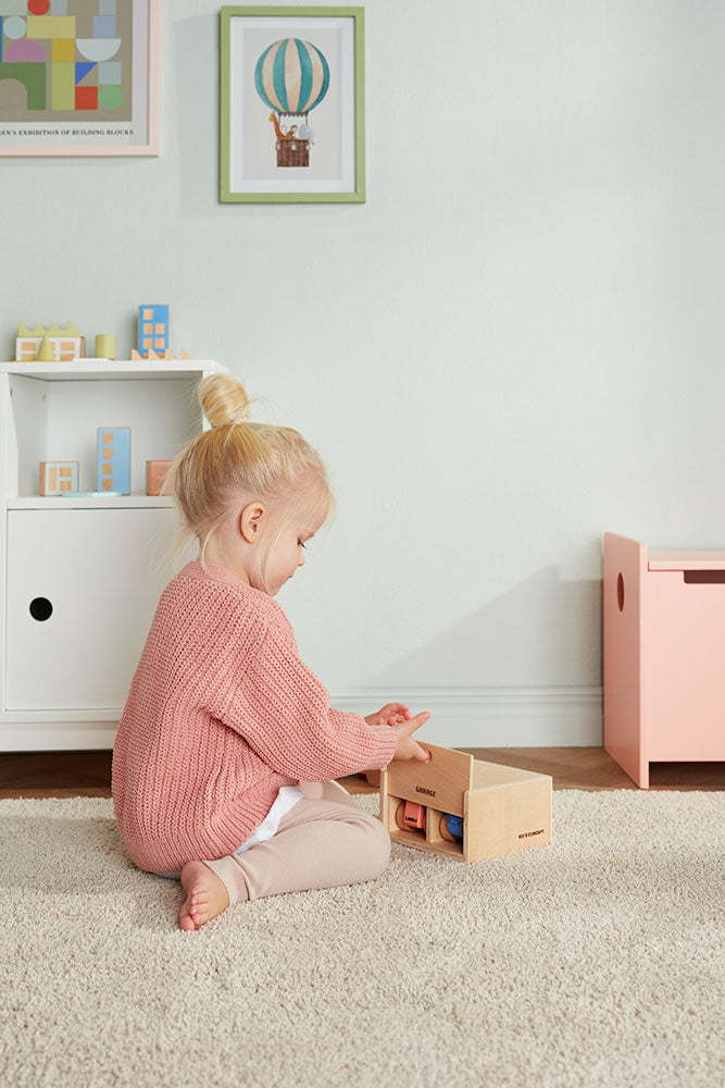 Child playing with a Kids Concept cars with garage play set in a neutral room
