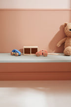 Kids Concept cars with garage play set and a teddy bear (not included) on a shelf against a pink wall