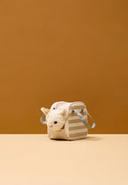 Kids Concept toy cat with carrier bag on a beige surface against an orange background