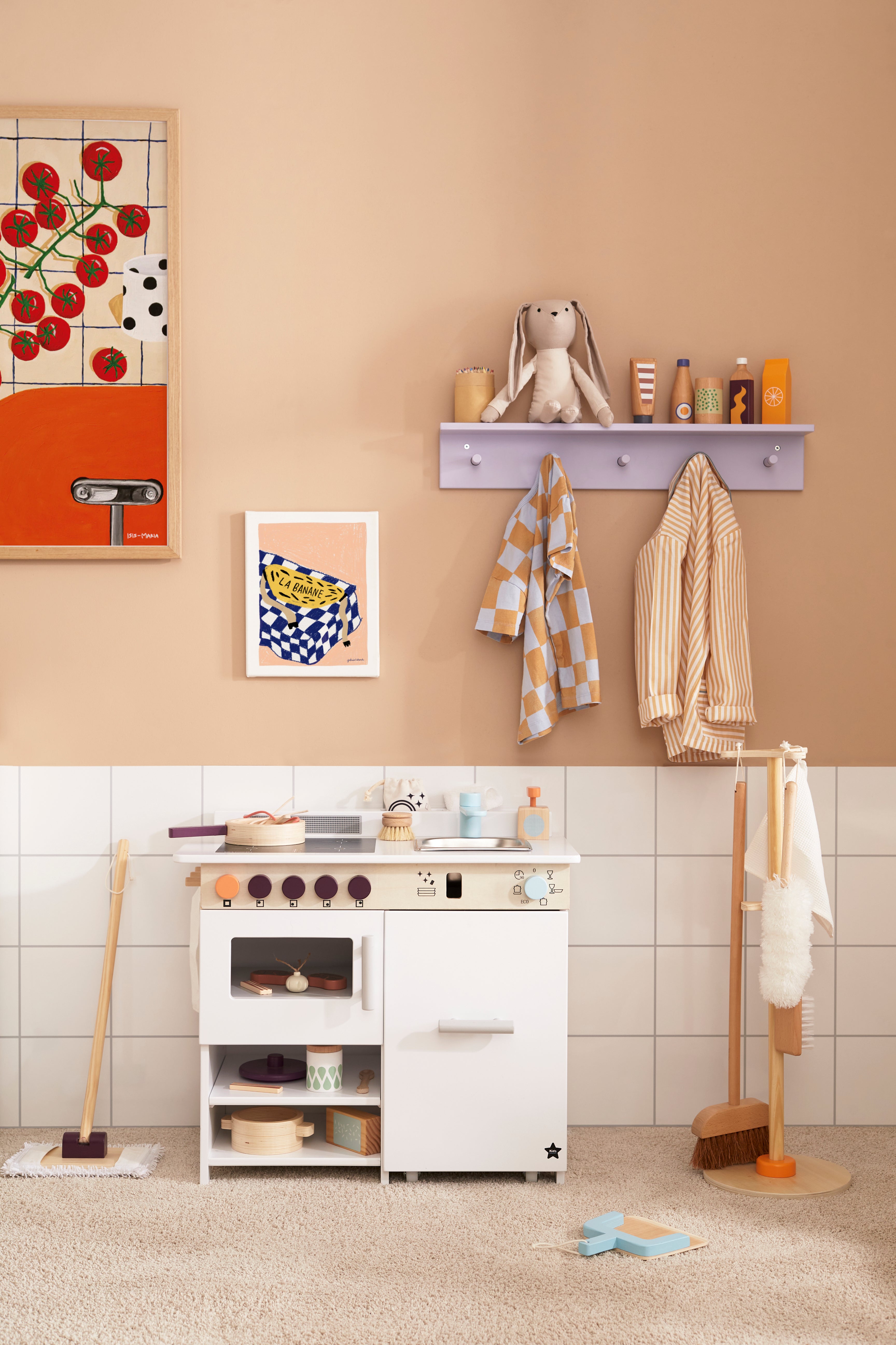 Children's playroom with a Kid's Concept cleaning set for kids, white cabinet, toys, and wall decorations