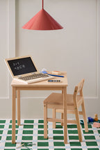 Children's desk with a Kid's Concept wooden computer play set, chair, and educational items on a green and white checkered floor