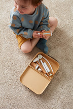 Child sitting on a carpet with a Kid's Concept doctor’s case play set in nature