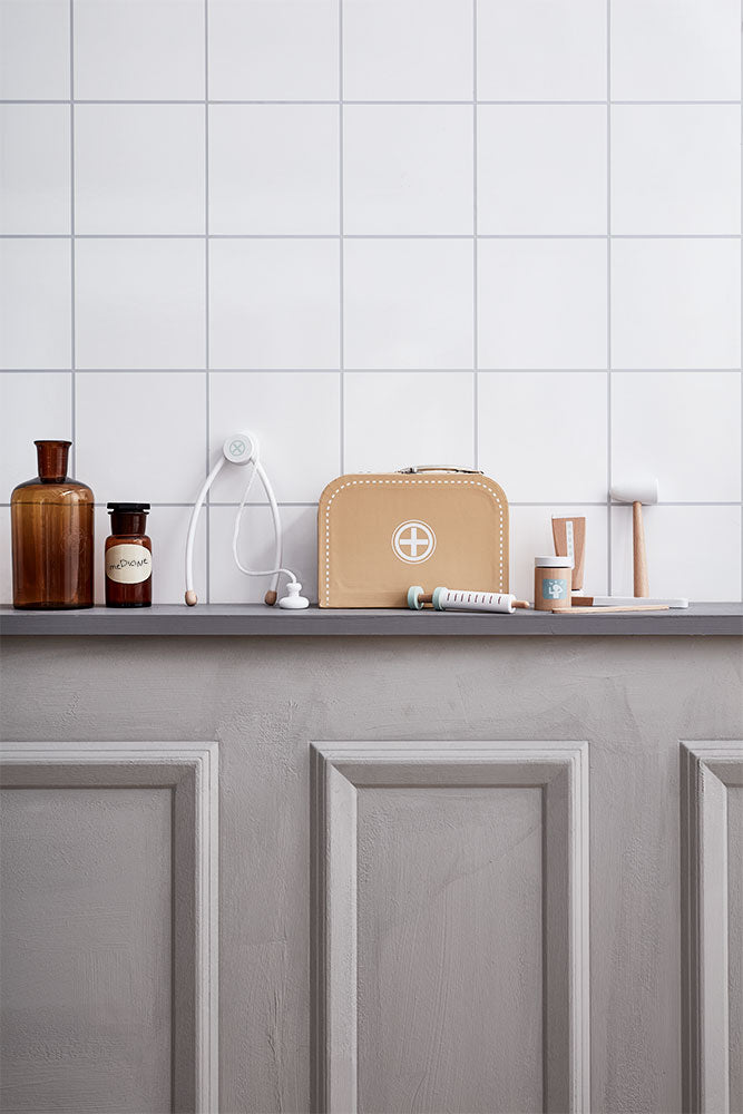 Kid's Concept doctor’s case play set in nature on a gray cabinet against a white tiled wall