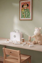 Children's play area with a table, chair, Kid's Concept doctor’s case play set in white, a toy sheep (not included) and a framed picture on the wall