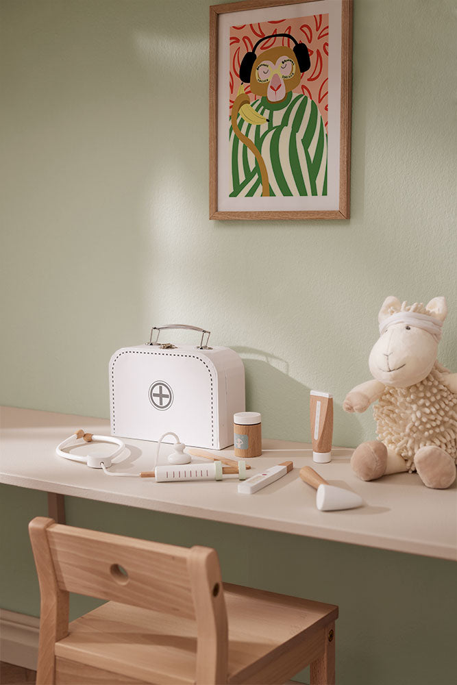 Children's play area with a table, chair, Kid's Concept doctor’s case play set in white, a toy sheep (not included) and a framed picture on the wall