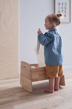 Child playing with a Kids Concept doll crib in a neutral room