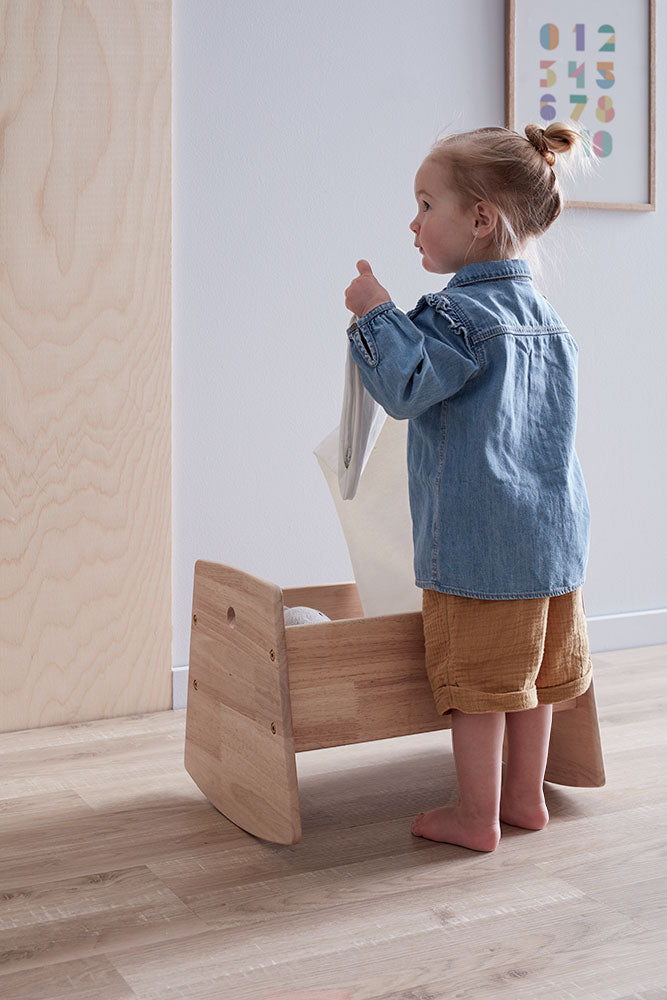 Child playing with a Kids Concept doll crib in a neutral room