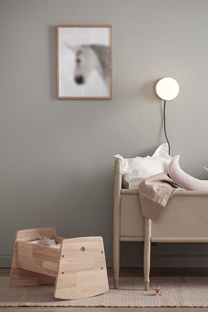 Children's room with Kids Concept doll crib, toy box, and bed against a gray wall