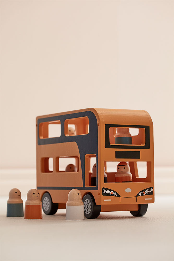 Kid's Concept wooden double decker bus toy with figures on a beige background