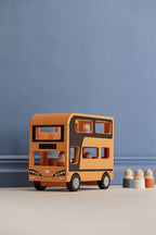 Kid's Concept wooden double decker bus toy with figures (included) on a blue and beige background