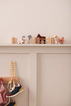 Kid's Concept wooden farm animals set on a shelf against a plain wall