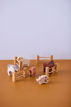 Kid's Concept wooden farm animals set on a brown surface with a light purple background