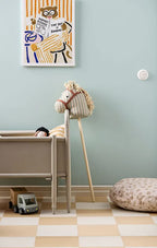 Children's room with a Kid's Concept hobby horse Sam, crib, and wall art on a light blue wall.