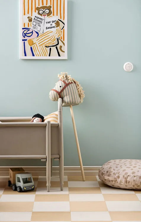 Children's room with a Kid's Concept hobby horse Sam, crib, and wall art on a light blue wall.