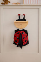 Kid's Concept ladybug dress-up costume hanging on a neutral wall