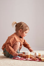 Child playing with Kid's Concept picnic play set on a light-colored carpet