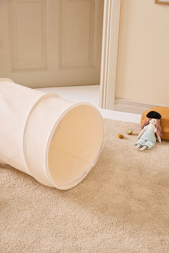 Kid's Concept kids play tunnel in off-white in a neutral-colored children's playroom