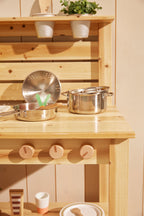 Kid's Concept pots and pans play set on a wooden surface with a light background