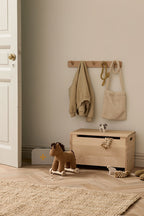 Wooden toy box with a Kid's Concept pull-along horse Vera, on a wooden floor in a room with a neutral color scheme