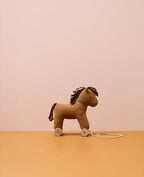 Kid's Concept pull-along horse Vera on a brown surface and pink background