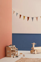 Children's playroom with a Kid's Concept ride-along kart and wooden toys (not included) against a colorful wall