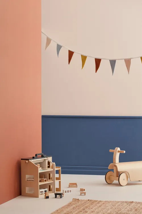 Children's playroom with a Kid's Concept ride-along kart and wooden toys (not included) against a colorful wall