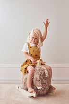 Child sitting on a Kid's Concept rocking horse Mammoth against a plain wall
