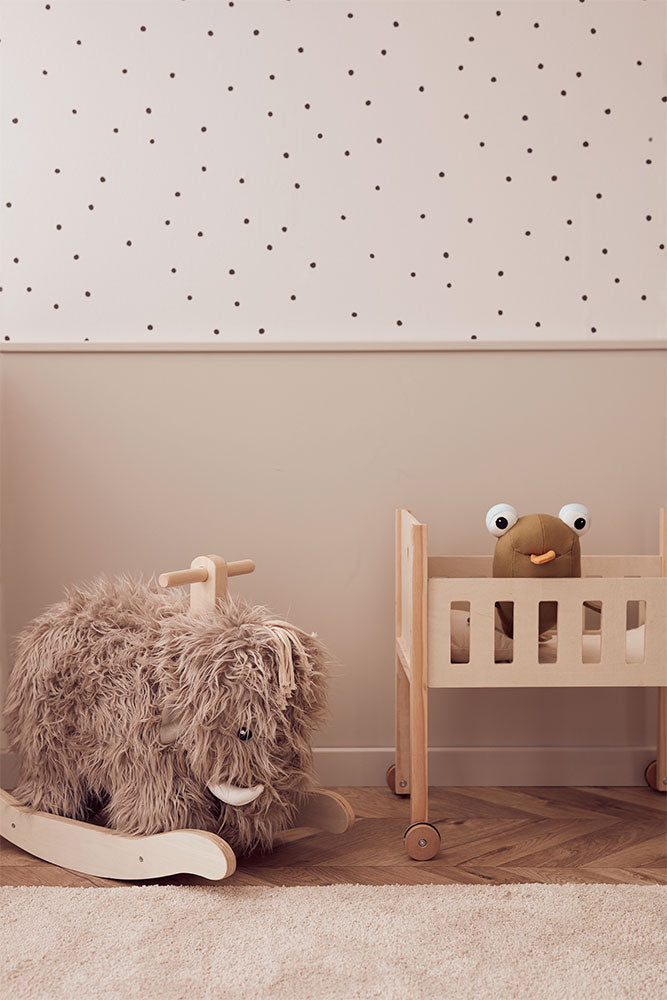 Children's room with a Kid's Concept rocking horse Mammoth and crib against a polka dot wall