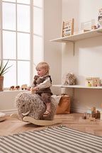 Child playing with a Kid's Concept rocking horse Mammoth in a bright room with large windows