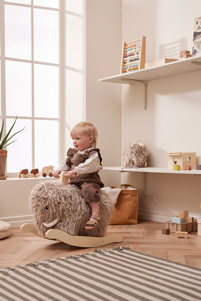 Child playing with a Kid's Concept rocking horse Mammoth in a bright room with large windows