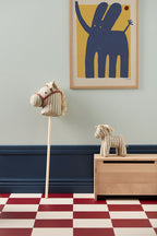 Children's room with Kid's Concept soft toy horse Sam and a hobby horse Sam (not included), abstract art on wall, and checkered floor