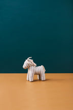 Kid's Concept soft toy horse Sam on a brown surface with a teal background