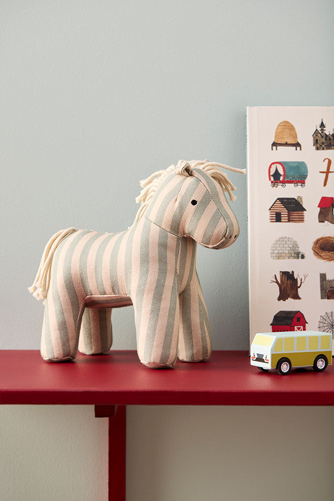 Kid's Concept soft toy horse Sam on a red shelf with a wall poster in the background