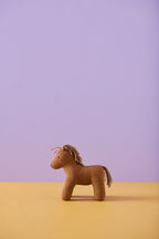 Kid's Concept soft toy horse Vera on a yellow surface with a purple background