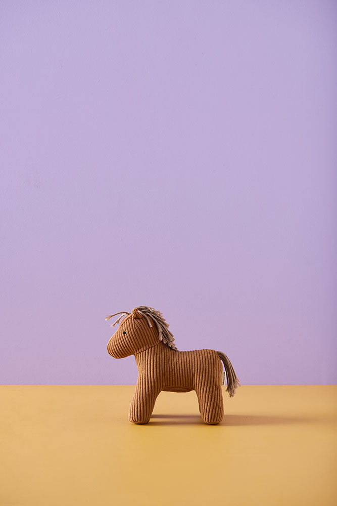 Kid's Concept soft toy horse Vera on a yellow surface with a purple background
