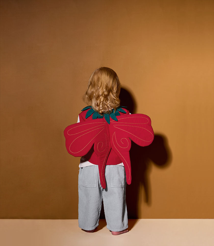 Child wearing a Kid's Concept strawberry fairy dress-up costume against a brown background